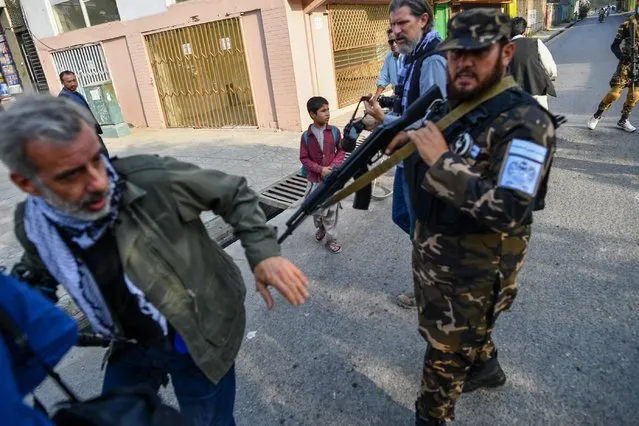 A member of the Taliban special forces pushes a journalist (L) covering a demonstration by women protestors outside a school in Kabul on September 30, 2021. (Photo by Bulent Kilic/AFP Photo)