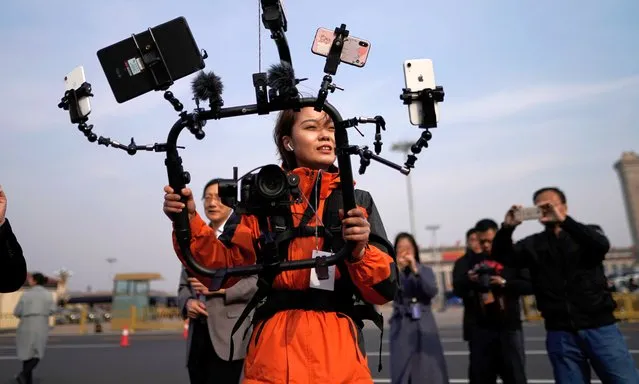 A media reporter uses mobile phones to do live broadcasts during the second plenary session of the 13th National People's Congress (NPC) outside the Great Hall of the People (GHOP) in Beijing, China, 08 March 2019. The NPC has over 3,000 delegates and is the world's largest parliament or legislative assembly though its function is largely as a formal seal of approval for the policies fixed by the leaders of the Chinese Communist Party. The NPC runs alongside the annual plenary meetings of the Chinese People's Political Consultative Conference (CPPCC), together known as “Lianghui” or “Two Meetings'”. (Photo by Wu Hong/EPA/EFE)