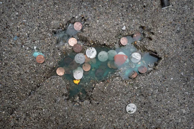 Coins are left behind by visitors at an impression in a sidewalk in the Roscoe Village neighborhood known as the Chicago Rat Hole on January 24, 2024 in Chicago, Illinois. The decades-old impression in the the shape of a rat (or squirrel) began attracting a regular stream of visitors after a post on X garnered more than 5 million views. (Photo by Scott Olson/Getty Images)