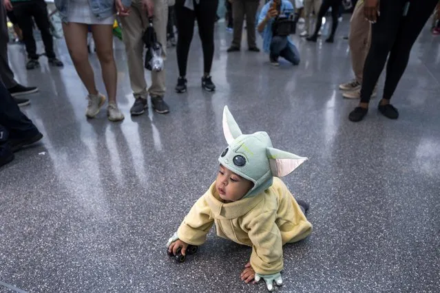 A baby dressed as Baby Yoda crawls on the floor of the Jacob K. Javits Convention Center during New York Comic Con at the on Sunday, October 10, 2021, in New York. (Photo by Charles Sykes/Invision/AP Photo)