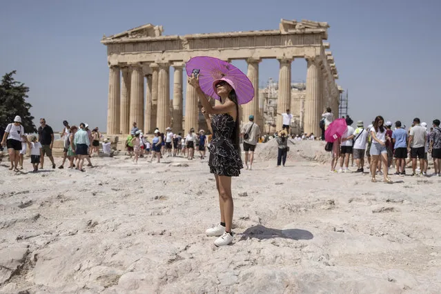 A woman takes a selfie in front of Parthenon temple atop of the ancient Acropolis hill during a heat wave in Athens, Greece, July 21, 2023. From April 1, 2024, Greece is planning to offer exclusive, guided tours of the Acropolis, its most powerful tourist magnet, to handfuls of well-heeled visitors outside normal opening hours. It will cost 5,000 euros ($5,500) for a group of up to five people. (Photo by Petros Giannakouris/AP Photo)