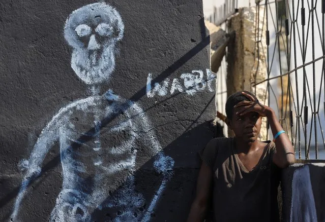 A man stands next to an illustration of a skeleton at a cemetery during Day of the Dead celebrations, in Port-au-Prince, Haiti on November 1, 2021. (Photo by Ralph Tedy Erol/Reuters)