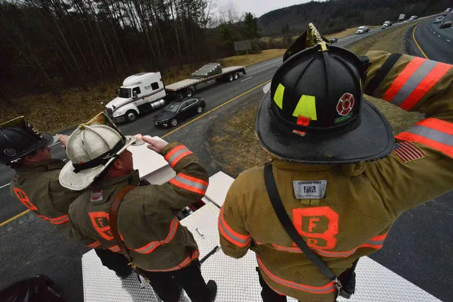 Members of the Brattleboro Fire Department and other agencies line up on sections of I-91 to salute a 9/11 monument as it makes its way from Barre, Vt., to New York City's 9/11 Museum on six flatbed trailers on Friday, April 5, 2019. (Photo by Kristopher Radder/The Brattleboro Reformer via AP Photo)
