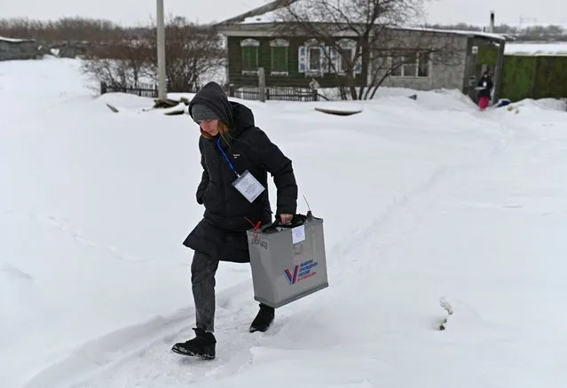 A member of a local electoral commission carrying a mobile ballot box leaves a house of local residents during the presidential election in the village of Novoaleksandrovka in the Omsk Region, Russia, on March 15, 2024. (Photo by Alexey Malgavko/Reuters)