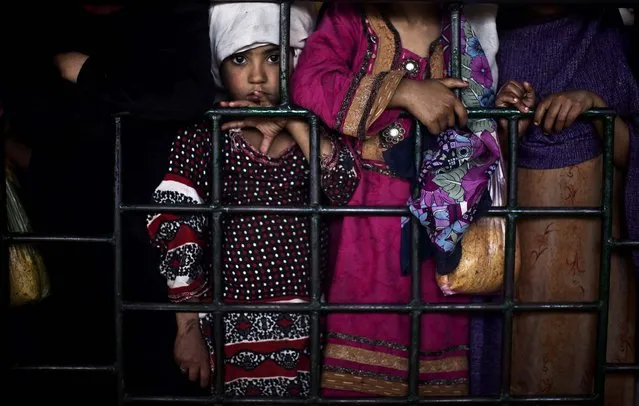 Sabah Farman, 6, stands between women waiting to receive a free ration of rice distributed at a shrine in Islamabad, Pakistan, on February 27, 2014. People who visit shrines and pray that their wishes are fulfilled usually offer food to be distributed to the poor. (Photo by Muhammed Muheisen/Associated Press)