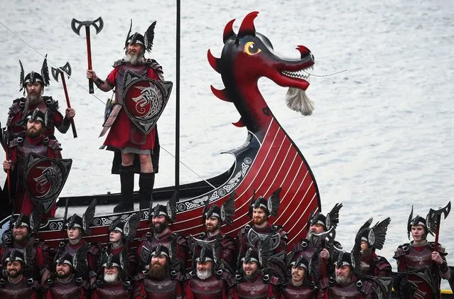 Members of the Up Helly Aa 'Jarl Squad' pose for photographs with their Viking galley ship in Lerwick, Shetland Islands on January 31, 2023 before the Up Helly Aa festival later in the day. Up Helly Aa celebrates the influence of the Scandinavian Vikings in the Shetland Islands and culminates with up to 1,000 'guizers' (men in costume) throwing flaming torches into their Viking longboat and setting it alight later in the evening. (Photo by Andy Buchanan/AFP Photo)