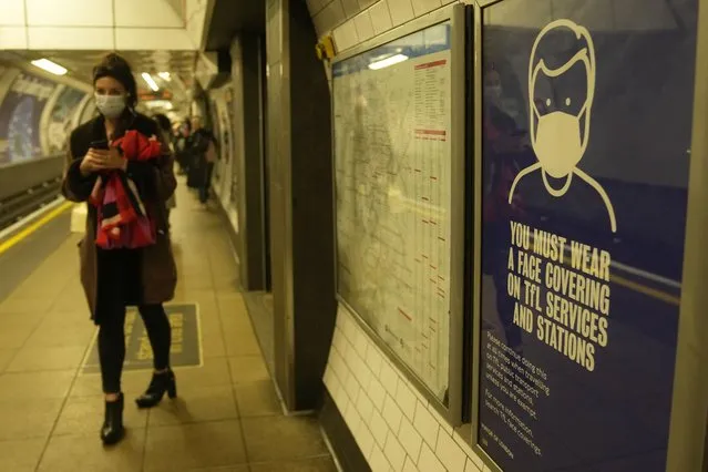 A commuter walks past a TFL (Transport for London)  information poster telling passengers that it is compulsory to wear a face mask on public transport to curb the spread of COVID-19, in London, Tuesday, November 30, 2021. The emergence of the new COVID-19 omicron variant and the world's desperate and likely futile attempts to keep it at bay are reminders of what scientists have warned for months: The coronavirus will thrive as long as vast parts of the world lack vaccines.(Photo by Alastair Grant/AP Photo)