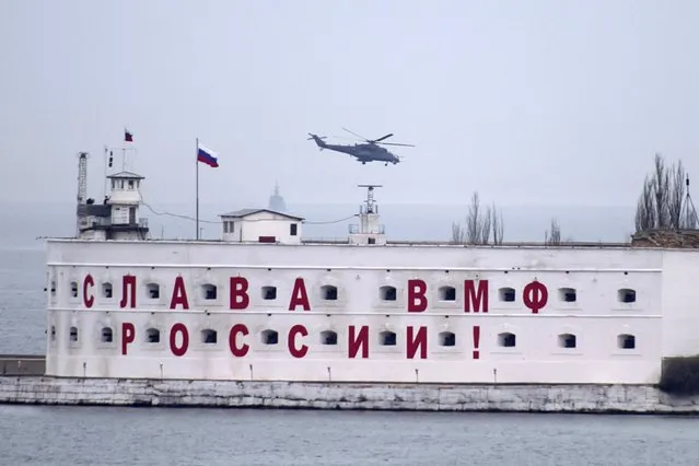 An attack helicopter, believed to Russian, flies over a Russian military base in at  Crimean port of Sevastopol March 6, 2014. (Photo by Baz Ratner/Reuters)