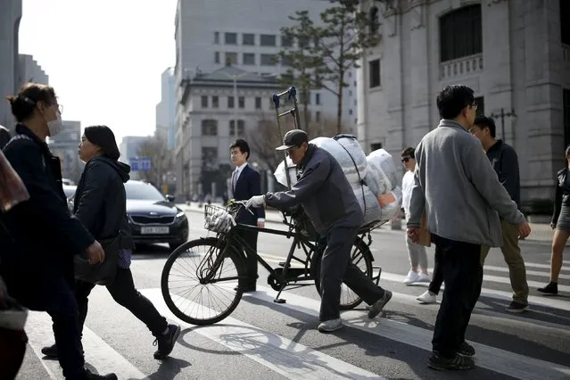 A man carrying his stuff on a bicycle crosses a zebra crossing in central Seoul, South Korea, March 31, 2016. South Korea's manufacturing activity contracted for a third straight month in March but at a much more moderate rate, suggesting some respite for the struggling trade-reliant economy, a private-sector survey showed on April 1, 2016. (Photo by Kim Hong-Ji/Reuters)