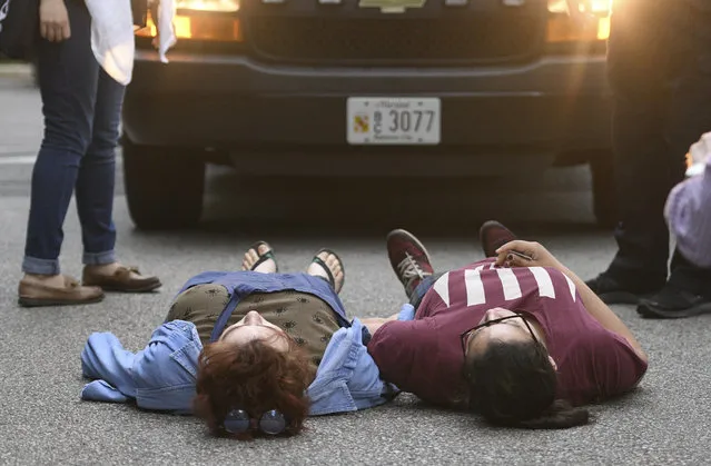 A pair of Hopkins students lay in the road in front of a police van carrying fellow protestors, Wednesday, May 8, 2019. Baltimore police arrested seven people as they ended a monthlong sit-in in the lobby of an administrative building at Johns Hopkins University, where protesters have demonstrated against the creation of a campus police force and the institution's contracts with the U.S. Immigrations and Customs Enforcement agency. (Photo by Jerry Jackson/The Baltimore Sun via AP Photo)