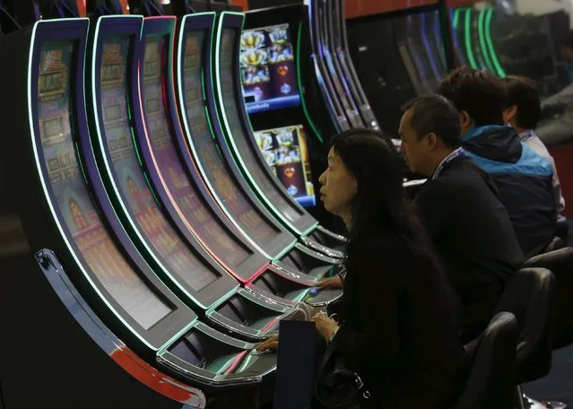 Visitors try slot machines at the Global Gaming Expo (G2E) Asia in Macau, China May 19, 2015. (Photo by Bobby Yip/Reuters)