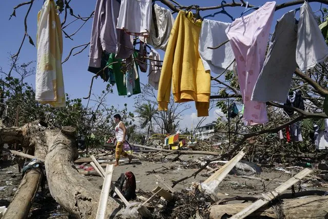 A woman walks past clothes that are left to dry on toppled trees due to Typhoon Rai in Talisay, Cebu province, central Philippines on Saturday December 18, 2021. (Photo by Jay Labra/AP Photo)
