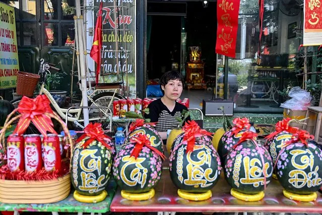 A woman selling decorated watermelons waits for customers in Hanoi on February 5, 2024, as Vietnamese prepare to celebrate their traditional Tet or Lunar New Year of the Dragon which falls on February 10. Peach blossoms and orange trees are two main ornaments at home for the lunar new year celebrations in Northern Vietnam. (Photo by Nhac Nguyen/AFP Photo)
