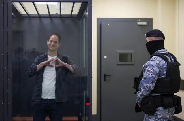 Wall Street Journal reporter Evan Gershkovich, who is in custody on espionage charges, makes a heart-shaped gesture inside an enclosure for defendants before a court hearing in Moscow, Russia, ob April 23, 2024. (Photo by Tatyana Makeyeva/Reuters)