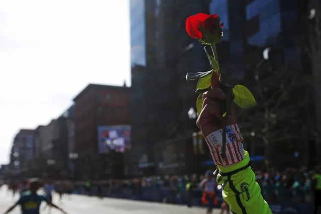 A runner holds up a rose as she finish the 120th running of the Boston Marathon in Boston, Massachusetts April 18, 2016. (Photo by Brian Snyder/Reuters)