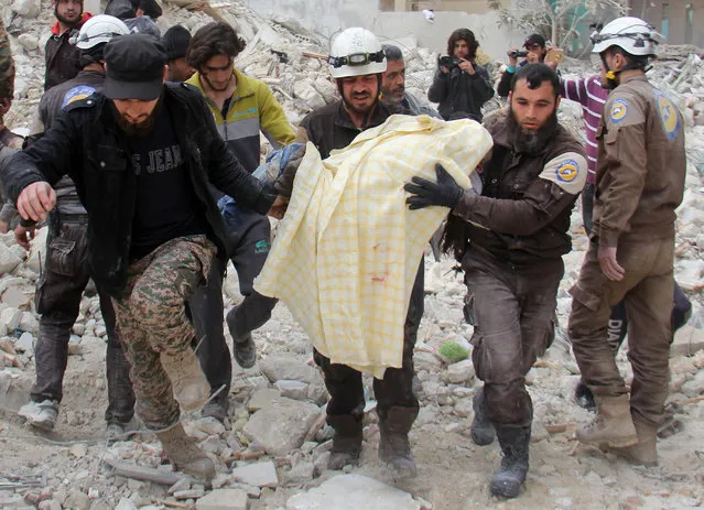 Members of the Syrian civil defence, known as the White Helmets, remove a victim from the rubble of a destroyed building following a reported air strike in the northwestern city of Idlib on March 15, 2017. (Photo by Omar Haj Kadour/AFP Photo)
