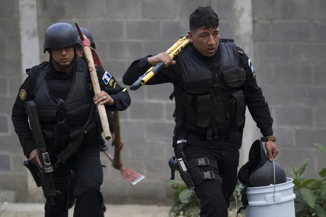 Police carry tools, including axes and a large plier, to use in an operation that aims to rescue four jail guards who were taken in the midst of a prison riot at the Centro Correccional Etapa II reformatory in San Jose Pinula, Guatemala, Monday, March 20, 2017. Using tear gas and guns, police entered the jail and successfully freed four jail guards, following a riot that broke out Sunday during which two jail monitors were killed, according Interior Minister Francisco Rivas. (Photo by Moises Castillo/AP Photo)