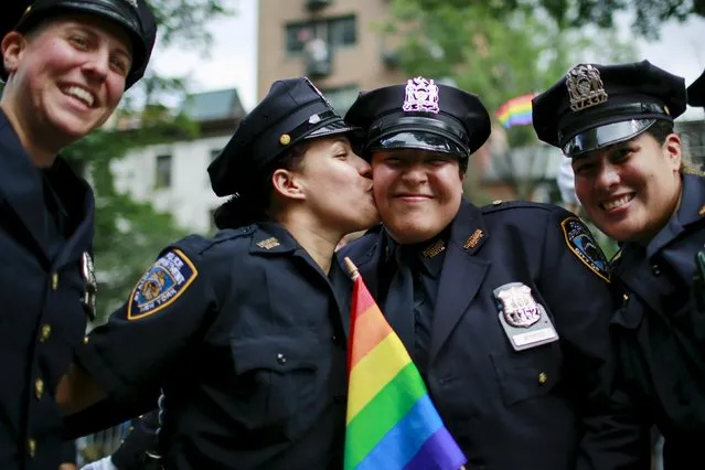 New York Police Department members kiss in front of Stonewall Inn during the annual Gay Pride Parade in New York June 28, 2015. (Photo by Eduardo Munoz/Reuters)