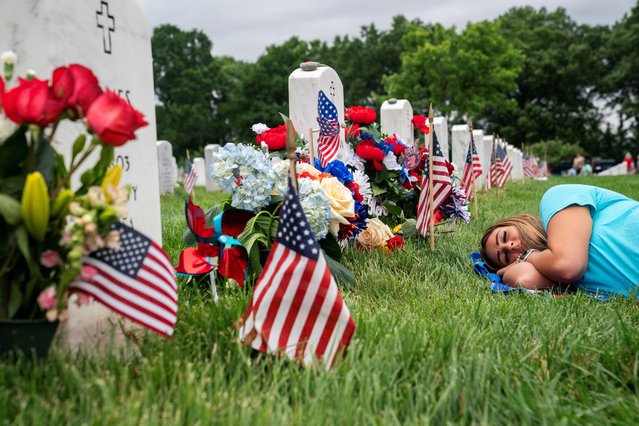 Sarah Schumann rests at the gravesite of her husband, Army Specialist Jordan Schumann, at Arlington National Cemetery on Memorial Day in Arlington, Virginia, on May 27, 2024. (Photo by Nathan Howard/Reuters)