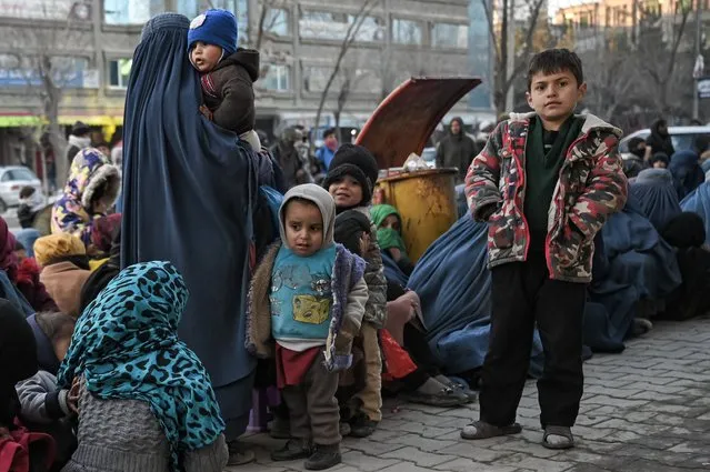 Children wait for free bread in front of a bakery in Kabul on January 24, 2022. (Photo by Mohd Rasfan/AFP Photo)