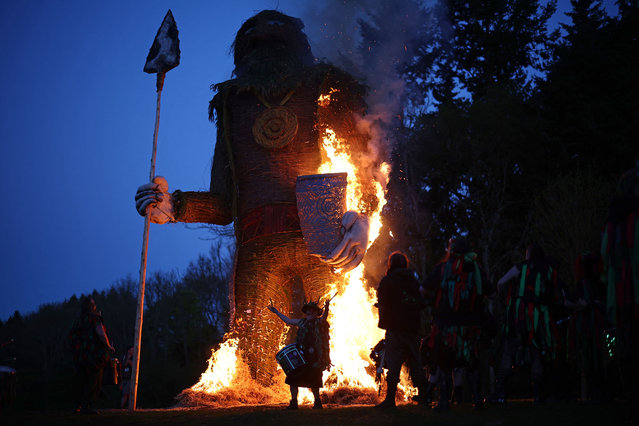 Drummers perform as the Wicker Man goes up in flames during the Celtic fire festival Beltain in Waterlooville, southern England on May 4, 2024. The festival, a modern annual participatory arts event, celebrates the Gaelic May Day festival and marks the beginning of summer. Historically it was widely observed in Ireland, Scotland and the Isle of Man. Rituals were performed to protect cattle, people and crops, and to encourage growth. Special bonfires were kindled, whose flames, smoke and ashes were deemed to have protective powers. The people and their cattle would walk around or between bonfires, and sometimes leap over the flames or embers. All household fires would be doused and then re-lit from the Beltane bonfire. (Photo by Henry Nicholls/AFP Photo)