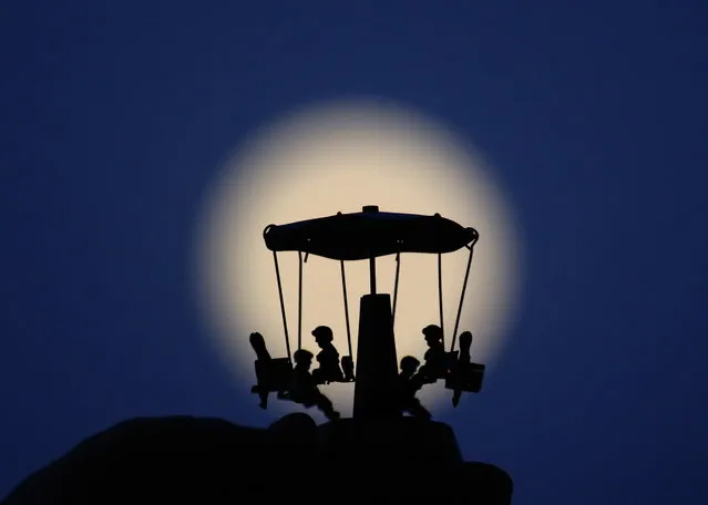 A full moon is seen through a carrousel in Nicosia, Cyprus 16 July 2019. The partial lunar eclipse on the night of 16 July 2019 will take place 50 years after the astronauts Neil Armstrong, Buzz Aldrin and Michael Collins launched aboard a Saturn V rocket toward the Moon on 16 July 1969. The year 2019 marks the 50th anniversary of the first moon landing on 20 July 1969. (Photo by Katia Christodoulou/EPA/EFE)