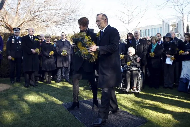 Australian Prime Minister Tony Abbott (C) and his wife Margaret prepare to lay a wreath for the Australian victims of Malaysia Airlines jet MH17 at a ceremony unveiling a memorial outside Parliament House in Canberra, Australia, July 17, 2015. Australia urged the United Nations Security Council on Tuesday to support the establishment of an international tribunal to prosecute those suspected of downing Malaysia Airlines jet MH17 in eastern Ukraine last year. (Photo by David Gray/Reuters)