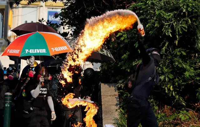 An anti-government demonstrator throws a petrol bomb towards Tsim Sha Tsui Police Station during a protest in Hong Kong, China, October 20, 2019. (Photo by Ammar Awad/Reuters)