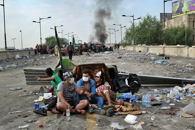 Anti-government protesters take cover while Iraqi Security forces close the bridge leading to the Green Zone, during a demonstration in Tahrir square, in Baghdad, Iraq, Sunday, October 27, 2019. (Photo by Hadi Mizban/AP Photo)