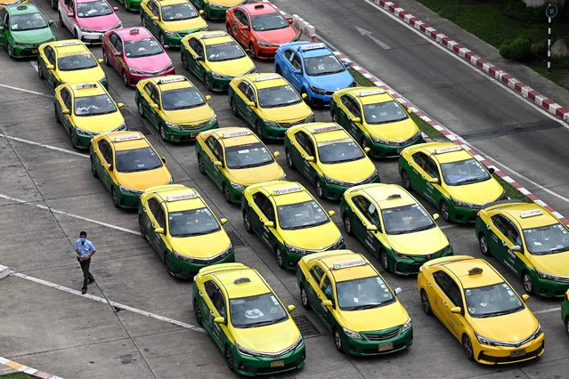 A driver (L) walks past as taxis wait in a queue at Don Mueang International Airport in Bangkok on June 25, 2024. (Photo by Manan Vatsyayana/AFP Photo)