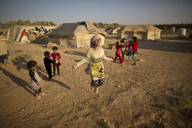 Syrian refugee girl, Zubaida Faisal, 10, skips a rope while she and other children play near their tents at an informal tented settlement near the Syrian border on the outskirts of Mafraq, Jordan, Sunday, July 19, 2015. (Photo by Muhammed Muheisen/AP Photo)