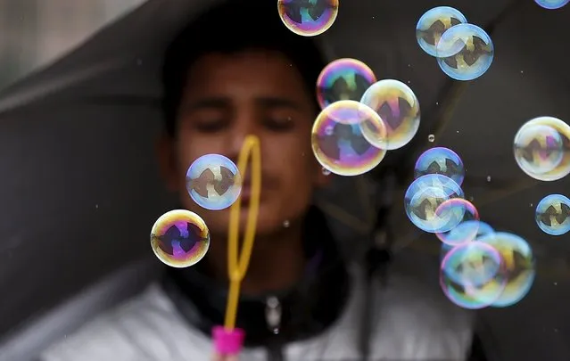 A street vendor blows bubbles to attract customers in Srinagar in the Kashmir region of India, March 20, 2016. (Photo by Danish Ismail/Reuters)