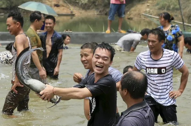 An ethnic Miao minority man (C) laughs as he catches a fish during an event celebrating the Naoyu Festival, in Rong'an county of Liuzhou, Guangxi Zhuang Autonomous Region, China, July 21, 2015. The traditional festival, with a history of over 400 years, is usually marked in the sixth month of the Chinese lunar calendar to celebrate the upcoming harvest. (Photo by Reuters/China Daily)