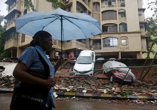 A woman walks past a collapsed wall due to heavy rains in Mumbai, India, July 21, 2015. (Photo by Danish Siddiqui/Reuters)