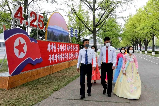 Citizens walk past celebrative posters displayed on the 90th founding anniversary of the Korean People's Revolutionary Army in Pyongyang, North Korea, Monday, April 25, 2022. The poster reads “Historic root of our revolution”. (Photo by Jon Chol Jin/AP Photo)