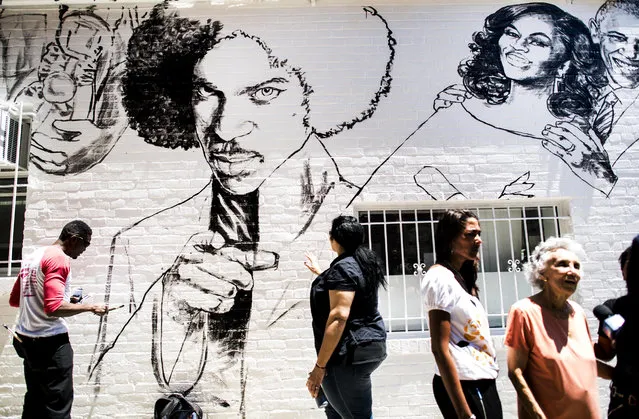 Muralist Aniekan Udofia, left, works on his new mural with art director Mia Duvall at Bens Chili Bowl on U Street NW while the matriarch Virginia Ali, surrounded by the Ali family, is interviewed by media in Washington, DC Friday June 2, 2017. (Photo by Melina Mara/The Washington Post via Getty Images)