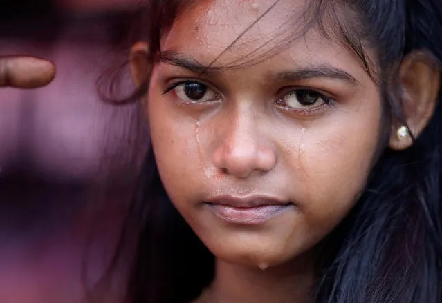 Sneha Mindani, 14, one of the survivors of the April 2019 Easter Sunday bomb attack, wipes her tears as her father delivers a speech during a protest to demand justice for this attack, on the third anniversary of the event, near the Presidential Secretariat, amid the country's economic crisis, in Colombo, Sri Lanka, April 17, 2022. (Photo by Navesh Chitrakar/Reuters)