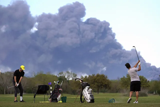Golfers practice at the Battleground Golf Course driving range as a chemical fire at Intercontinental Terminals Company continues to send dark smoke over Deer Park, Texas, Tuesday, March 19, 2019. (Photo by Melissa Phillip/Houston Chronicle via AP Photo)