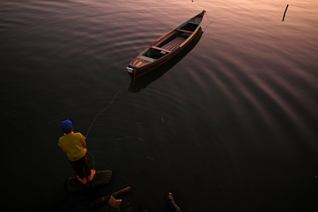 An Iraqi fisherman ties his boat to a wooden plank in the Shatt al-Arab river, formed at the confluence of the Tigris and Euphrates rivers, in Iraq's southern city of Basra, on August 12, 2024. (Photo by Hussein Faleh/AFP Photo)