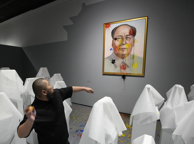 Chinese dissident artist Badiucao throws paintballs at an image of Mao Zedong in a performance for reporters ahead of the opening of a new exhibition in Warsaw, Poland on Friday, June 16, 2023. The museum faced demands from the Chinese embassy not to open the exhibition, “Tell China's Story Well”, which is highly critical of China's human rights record. (Photo by Czarek Sokolowski/AP Photo)