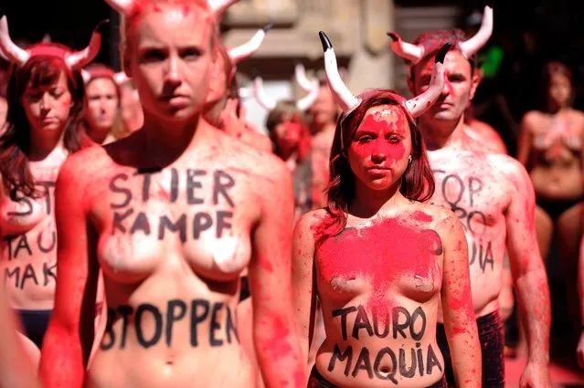 Pro-animal rights activists stand after spreading red powder on themselves and breaking fake “banderillas” (spears to jab the bull) to protest against bullfighting and bull-running during a demonstration called by the People for the Ethical Treatment of Animals (PETA) and Anima Naturalis pro-animal groups on the eve of the San Fermin festivities in the Northern Spanish city of Pamplona on July 5, 2017. The San Fermin festival is a symbol of Spanish culture that attracts thousands of tourist to watch the bull-runs despite heavy condemnation from animal rights groups. (Photo by Ander Gillenea/AFP Photo)