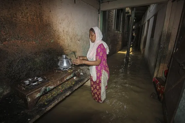 A woman cooks outside her home in a flooded corridor following heavy rainfalls in Sylhet on May 19, 2022. (Photo by Mamun Hossain/AFP Photo)