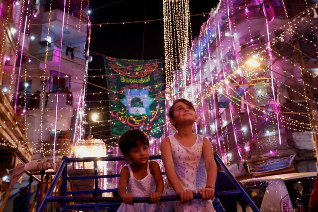 Siblings ride on a swing as they visit an illuminated street ahead of Eid-e-Milad-ul-Nabi, the birth anniversary of Prophet Mohammad, in Karachi, Pakistan on September 15, 2024. (Photo by Akhtar Soomro/Reuters)