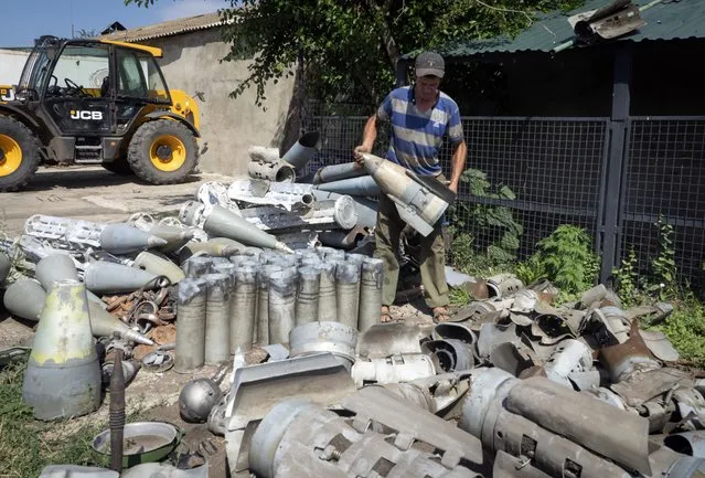 A farmer collects fragments of Russian rockets that he found on his field ten kilometres from the front line in the Dnipropetrovsk region, Ukraine, Monday, July 4, 2022. (Photo by Efrem Lukatsky/AP Photo)