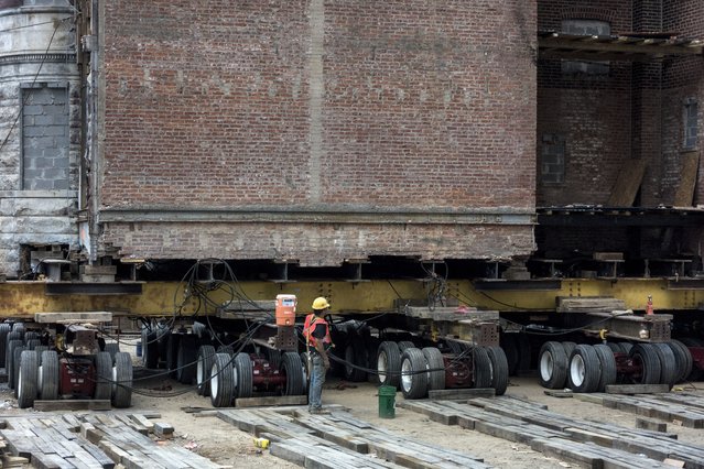 A worker stands by a historic building as it is moved down the block on wheels on New York Avenue to make way for a new construction July 28, 2014 in Washington, DC. (Photo by Brendan Smialowski/AFP Photo)