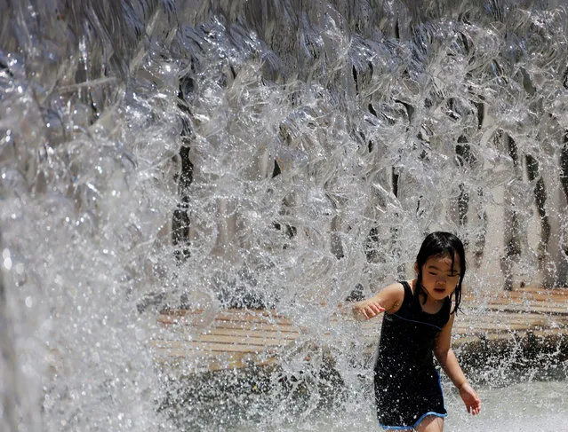 A girl plays at a fountain to cool off herself at a park, under the strain of Tokyo's hottest June streak since 1875, in Tokyo, Japan, June 30, 2022. (Photo by Kim Kyung-Hoon/Reuters)