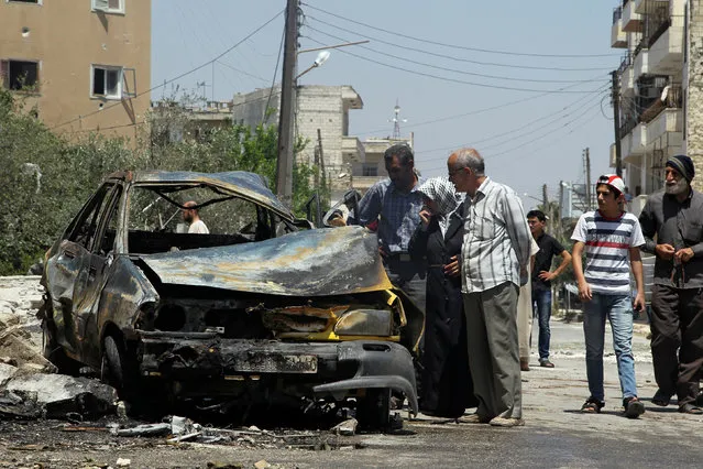 Civilians inspect a burnt car at a site hit by an airstrike in the rebel-controlled city of Idlib, Syria June 29, 2016. (Photo by Ammar Abdullah/Reuters)