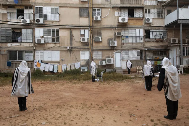 Ultra-Orthodox Jews keep social distancing during a morning prayer next to their houses as synagogues are closed following the government's measures to help stop the spread of the coronavirus, in Bnei Brak, Israel, Friday, April 24, 2020. (Photo by Oded Balilty/AP Photo)