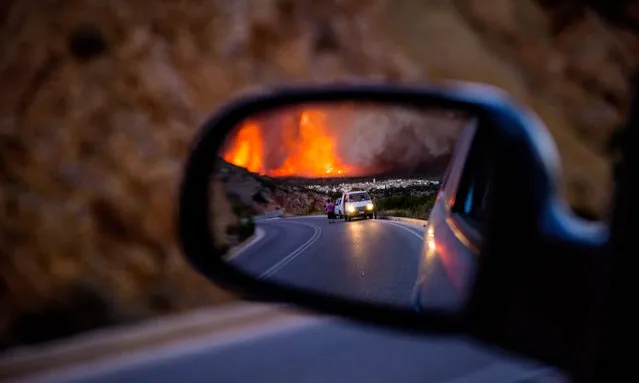A picture made available on 26 July 2016 shows citizens wathcing the dense smoke over Lithi village, as reflected in a mirror of a car, during a wildfire on Chios island, Greece, 25 July 2016. The huge wildfire that broke out early 25 July 2016, on the island of Chios which has burned 3,500 hectares of forest and farm land, set under control. Over 90 percent of the mastic trees at the villages of Lithi, Elata and Vessa were destroyed while a large number of mastic trees were burned at the villages of Mesta, Armolia and Pyrgi. (Photo by Kostas Koyrgias/EPA)