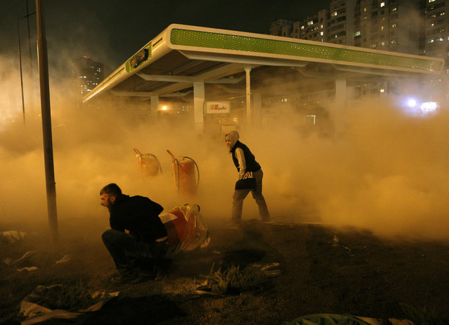 Protestors set off a fire extinguisher toward a petrol station under construction in a densely populated area in Kiev, Ukraine, late Wednesday, October 4, 2017. Activists claimed that private gas company OKKO started the construction without a permission from the city authorities. (Photo by Efrem Lukatsky/AP Photos)